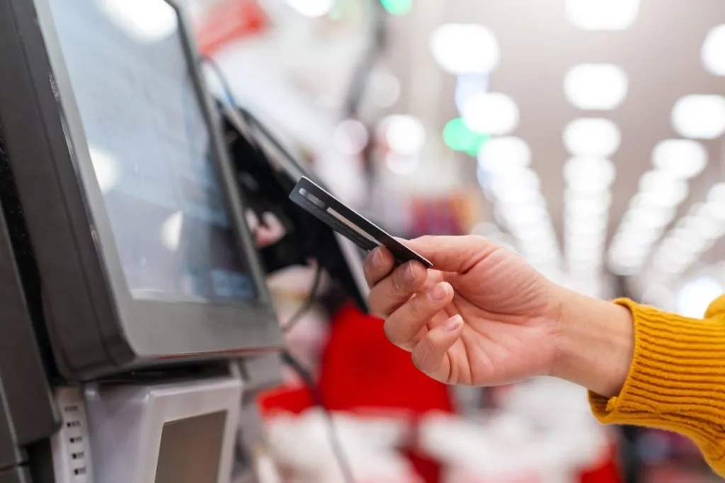 mão feminina em close fazendo compra com cartão de crédito no self checkout